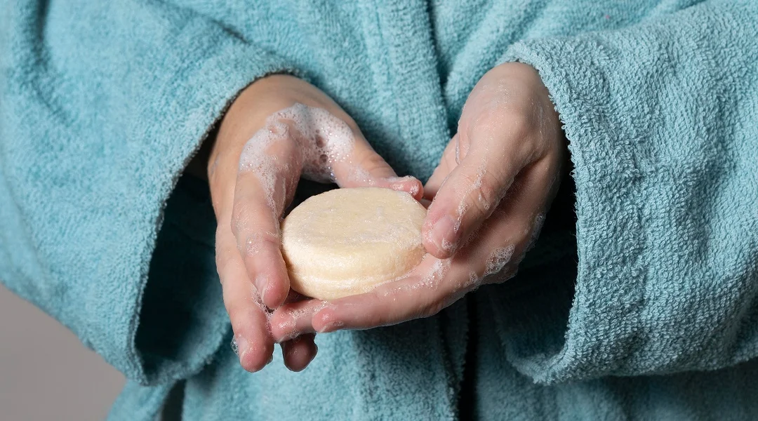 Une personne en peignoir tenant une barre de savon.