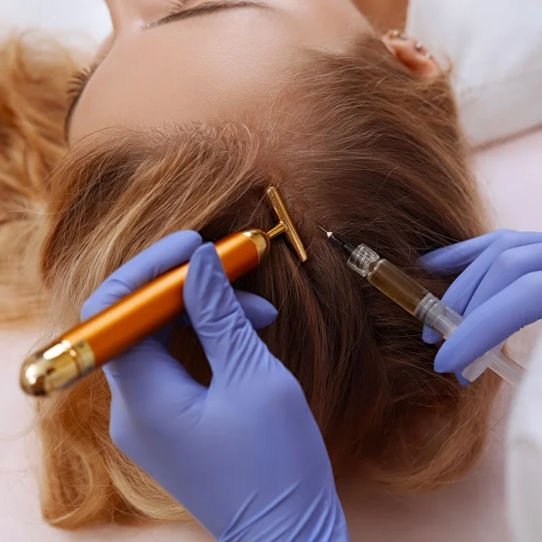 A woman receiving a hair treatment from a doctor in a clinical setting, focused on her hair and the doctor's expertise.