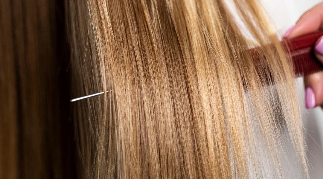 A woman using a comb to cut her hair, focused on achieving a precise hairstyle.